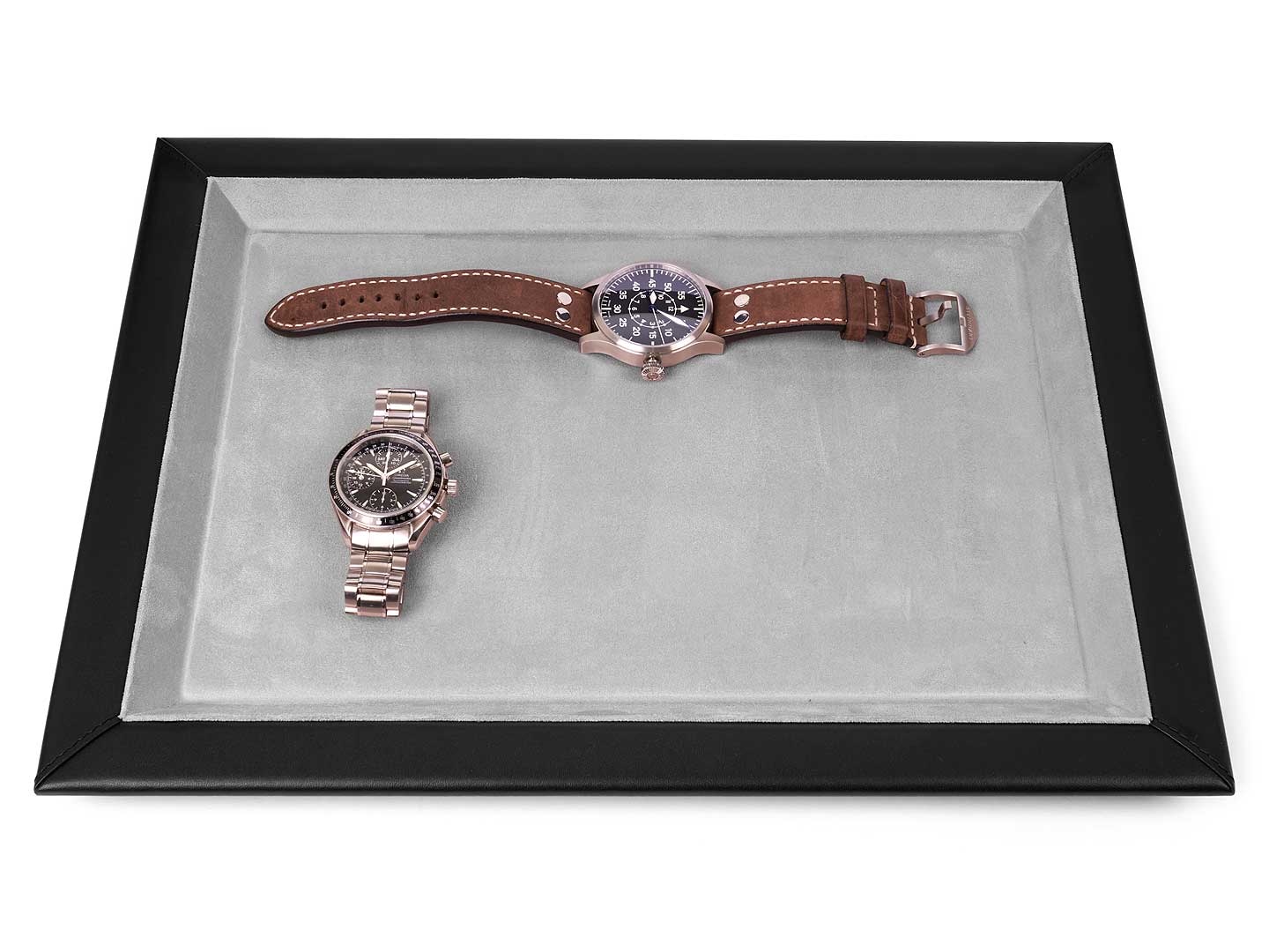 Two watches displayed in a black framed leather watch on a white background