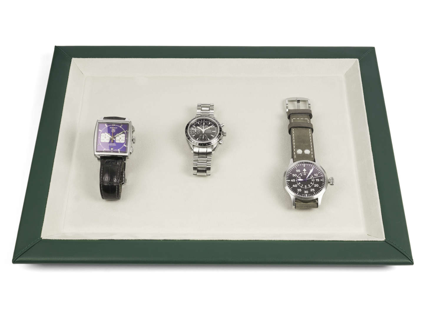 Green leather watch presentation tray with beige interior and 3 watches on it 